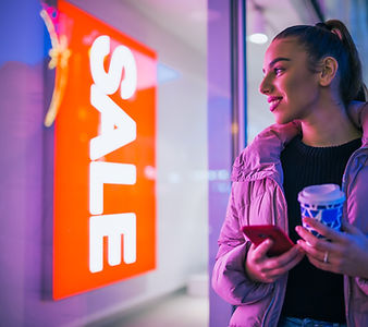 Woman with smartphone looking at sale sign
